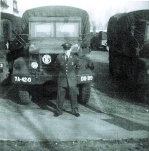 a man in military uniform standing in front of a military vehicle