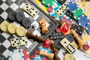 Various board games like chess, checkers, and dominios in a pile.