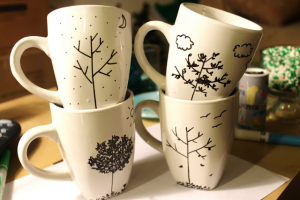 4 mugs stacked in pairs with various tree designs on them.