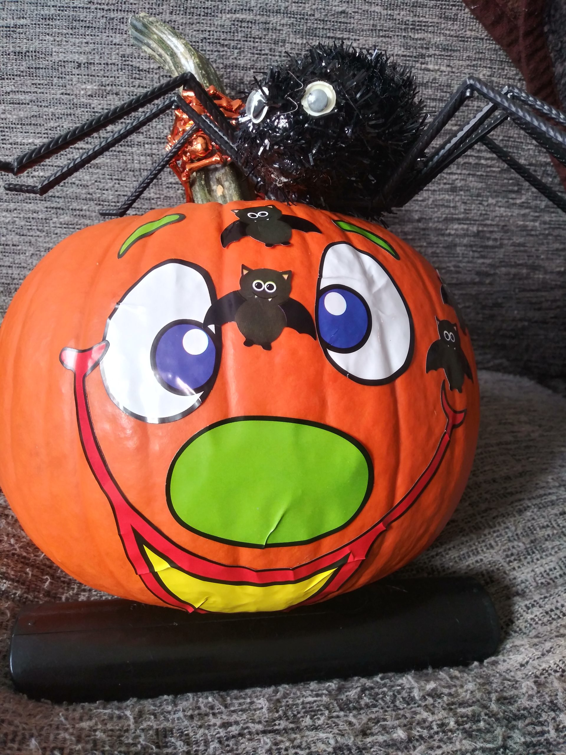 A pumpkin decorated with a clown face with a spider on top of it