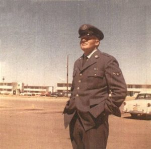 a man in military uniform standing in front of parked cars