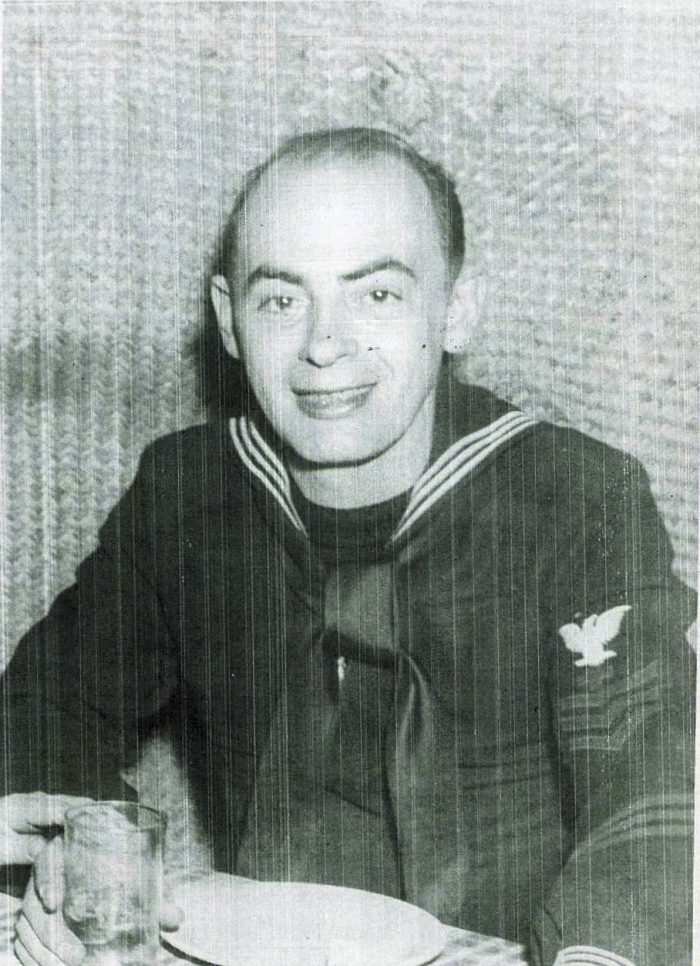 a man in military uniform sitting at a table holding a glass