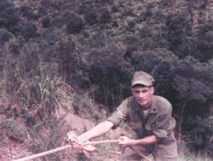 a man in military uninform pulling on a rope on the side of a hill