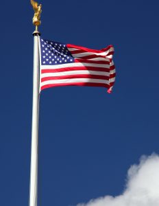 a flag pole with an american flag blowing in the wind