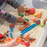 Unrecognizable children play in sensory bin