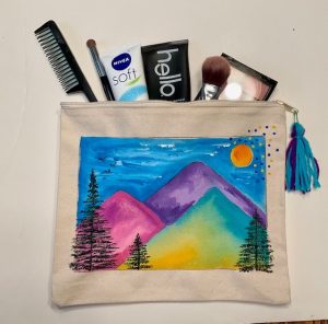 A zippered pouch painted with a mountain scene to hold makeup or other travel essentials.