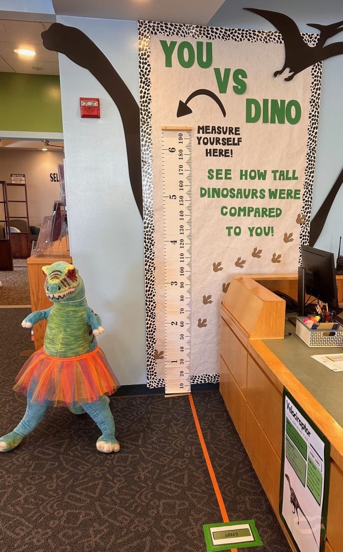 You Vs Dino bulletin board with measuring tape and toy dinosaur