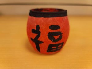 Votive candle holder decorated with felt and Chinese characters.