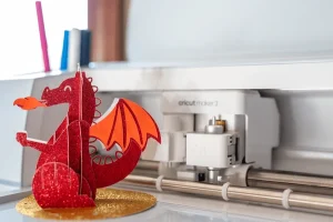 A Cricut machine with a 3 dimensional paper cut-out dragon in front of it.