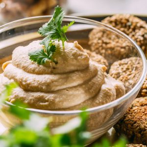 Hummus in a bowl with snacks around it.