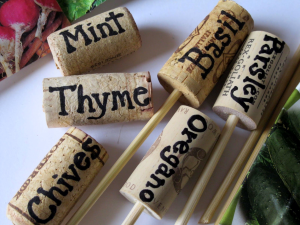 Wine bottle corks with various herb names written on them in black marker.