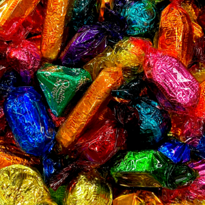 Chocolate pieces wrapped in different colored wrappers - pink, orange, blue, green, yellow, and purple.