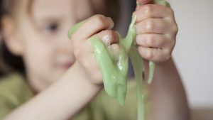 Child squeezing novelty green slime through fingers