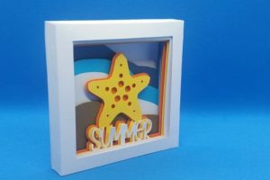 A shadowbox with beach waves as the background and a starfish with the word summer underneath it in the foreground. 