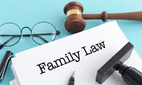 Family law written at the top of a white piece of paper with a gavel, pen, stamp, and glasses around it.