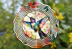 A wind spinner with a picture of a hummingbird hanging outdoors.