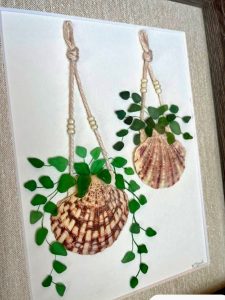 Two seashells glued to canvas to make them look like pots with rope hangers, and leaves painted on the canvas coming out of the shells.
