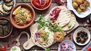 Middle eastern, Arabic or Mediterranean appetizers table concept with falafel, pita flatbread, bulgur and tomato salads, grilled vegetables, stuffed grape leaves,olives and nuts.