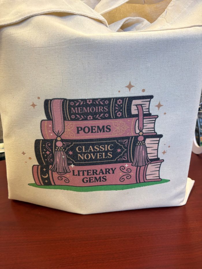 A tote bag with a stack of 4 books with Memoirs, Poems, Classic Novels, and Literary Gems written on the spine.