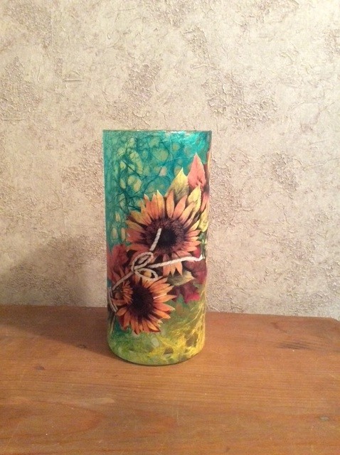 A tall, round vase decorated with painted sunflowers and a blue background